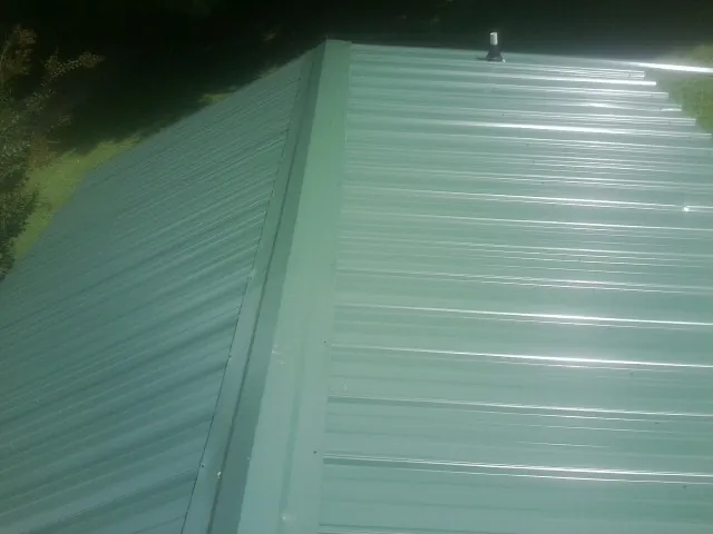 New green metal panels meeting at the ridge of a roof — Flat Roof Repair work by our crew in Folsom