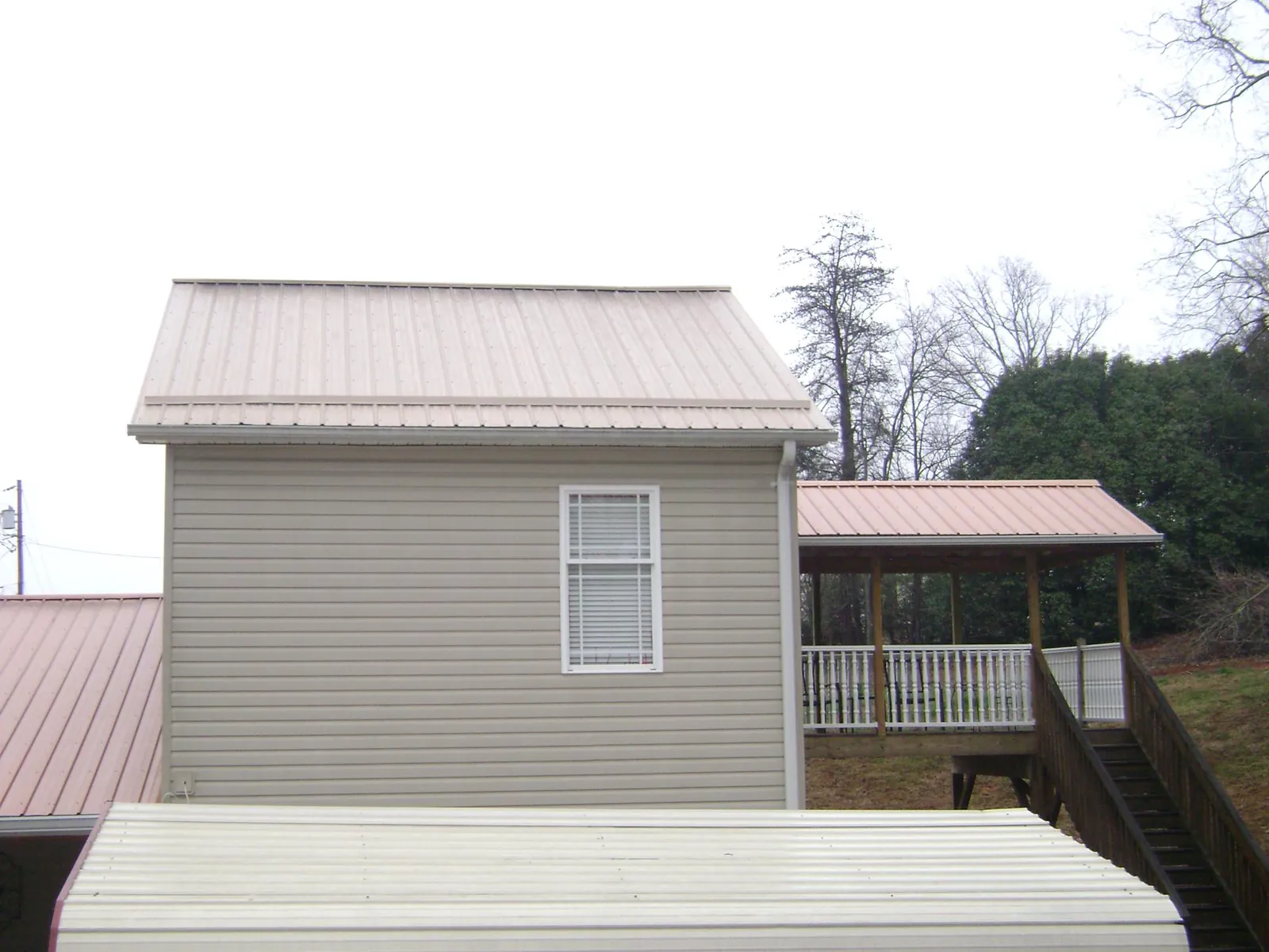 Tan metal roofs on a two story addition and attached porch, from a Roof Replacement job in Folsom