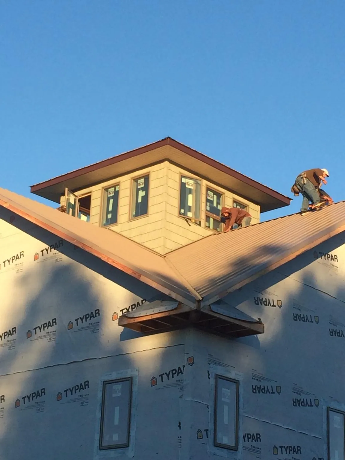 Roofers working around a rooftop cupola on a new metal roof at sunset — Roof Waterproofing in Folsom by Roofing Brothers